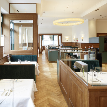 A black pan with a gratinated cheese plate, garnished with herbs, on a wooden board.